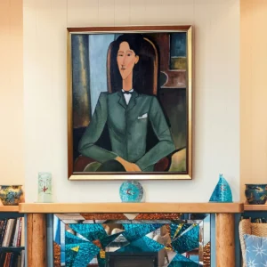 Framed reproduction of Modigliani’s "Portrait of Jean Cocteau" with gold frame, displayed in a modern living room.
